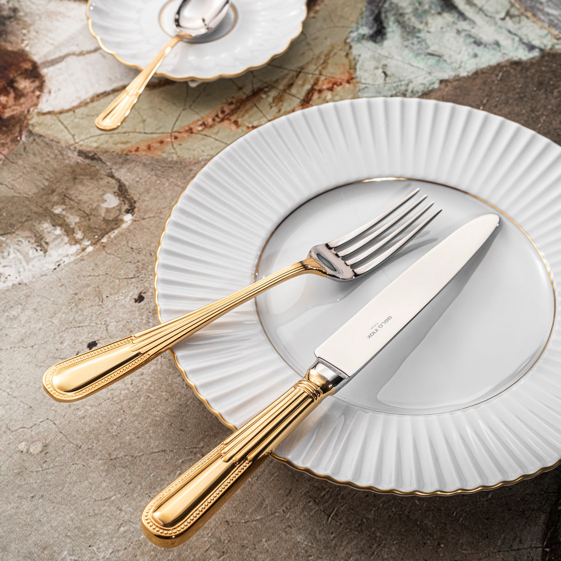 Belo Inox Alma cutlery with 24K gold plated handles placed on white ceramic plates in an elegant table setting