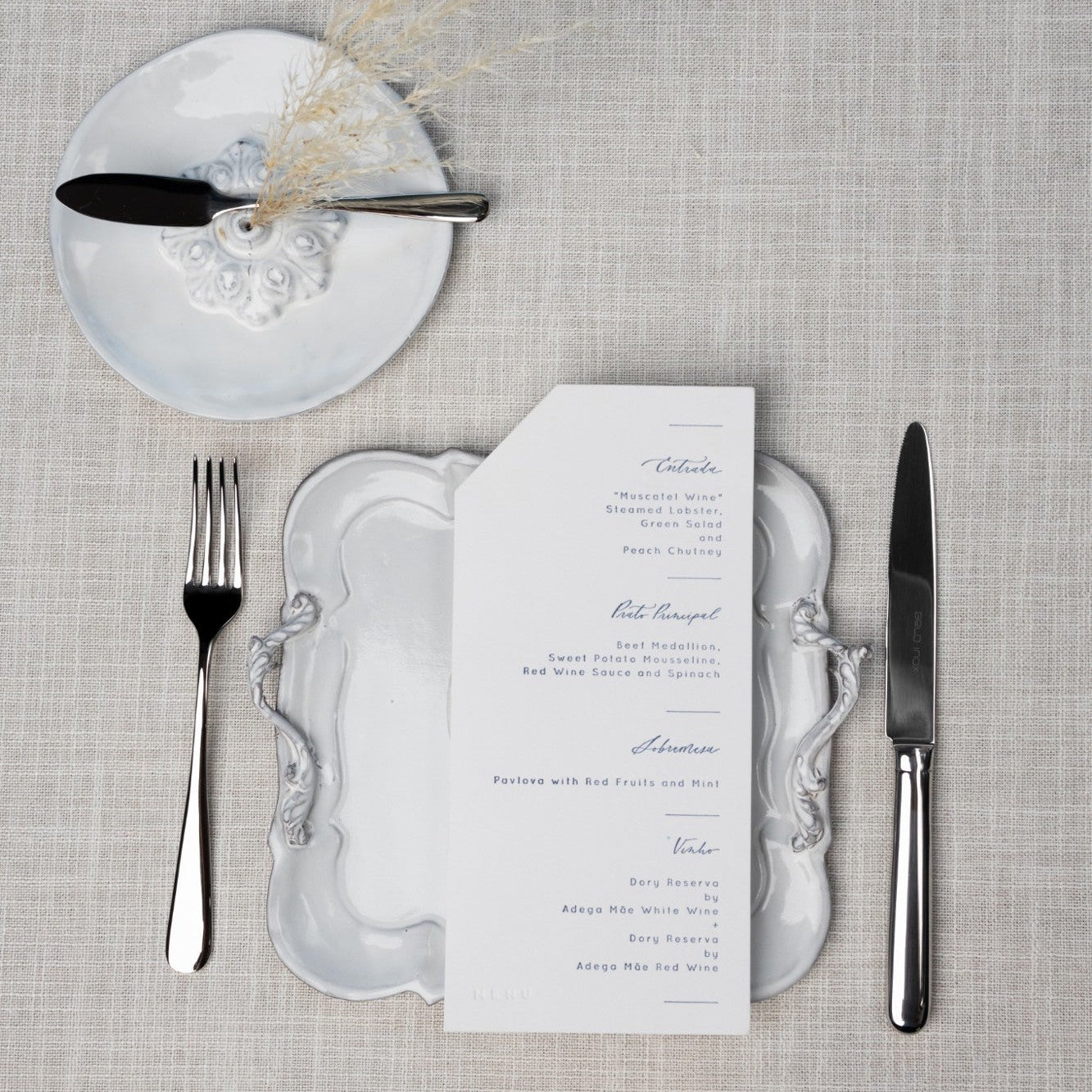 Belo Inox Belo 9 polished stainless steel cutlery set arranged on a refined white plate with a menu – classic fine dining table setting