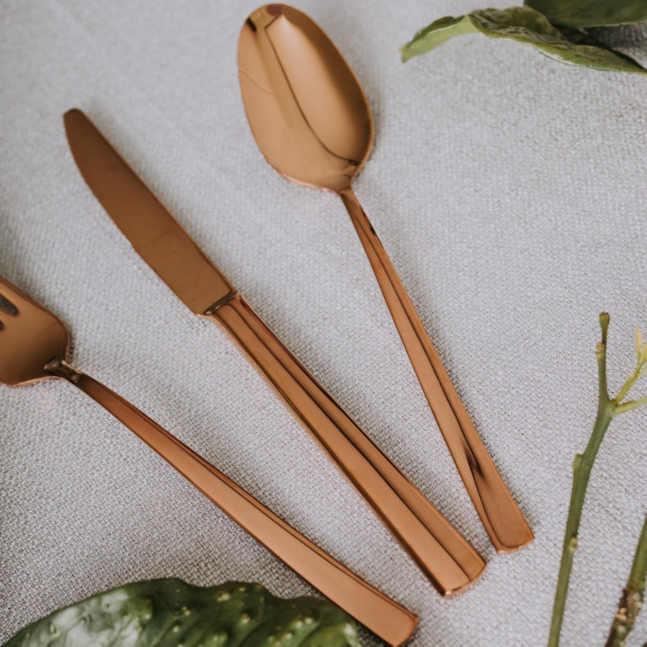 Close-up of Belo Inox Belo 12 PVD copper cutlery showing mirror-polished finish on a soft textured tablecloth.