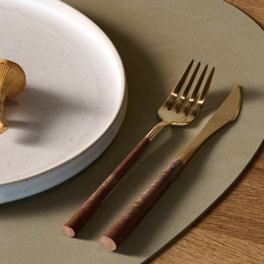 Close-up of the Belo Inox Neo Brown Gold table fork and knife with wooden handles, styled on a neutral plate and placemat.
