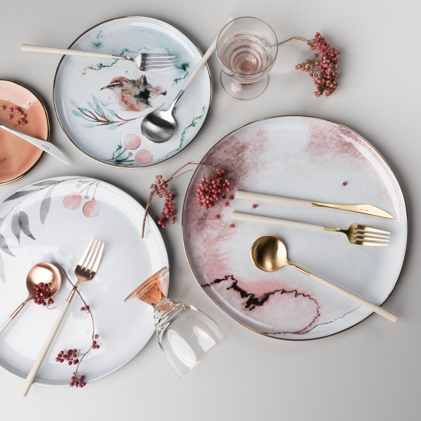 Belo Inox NEO Gold cutlery set placed on a pink and white ceramic plate with decorative details, lifestyle table setting.
