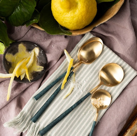 Belo Inox NEO Green cutlery with brushed gold finish displayed on a striped cloth with lemons and zest. Lifestyle photo by Bright Kitchen.

