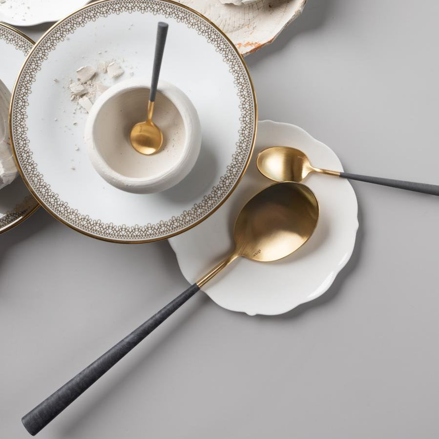 Belo Inox Neo Grey Gold cutlery set with brushed gold heads and grey resin handles displayed on white plates