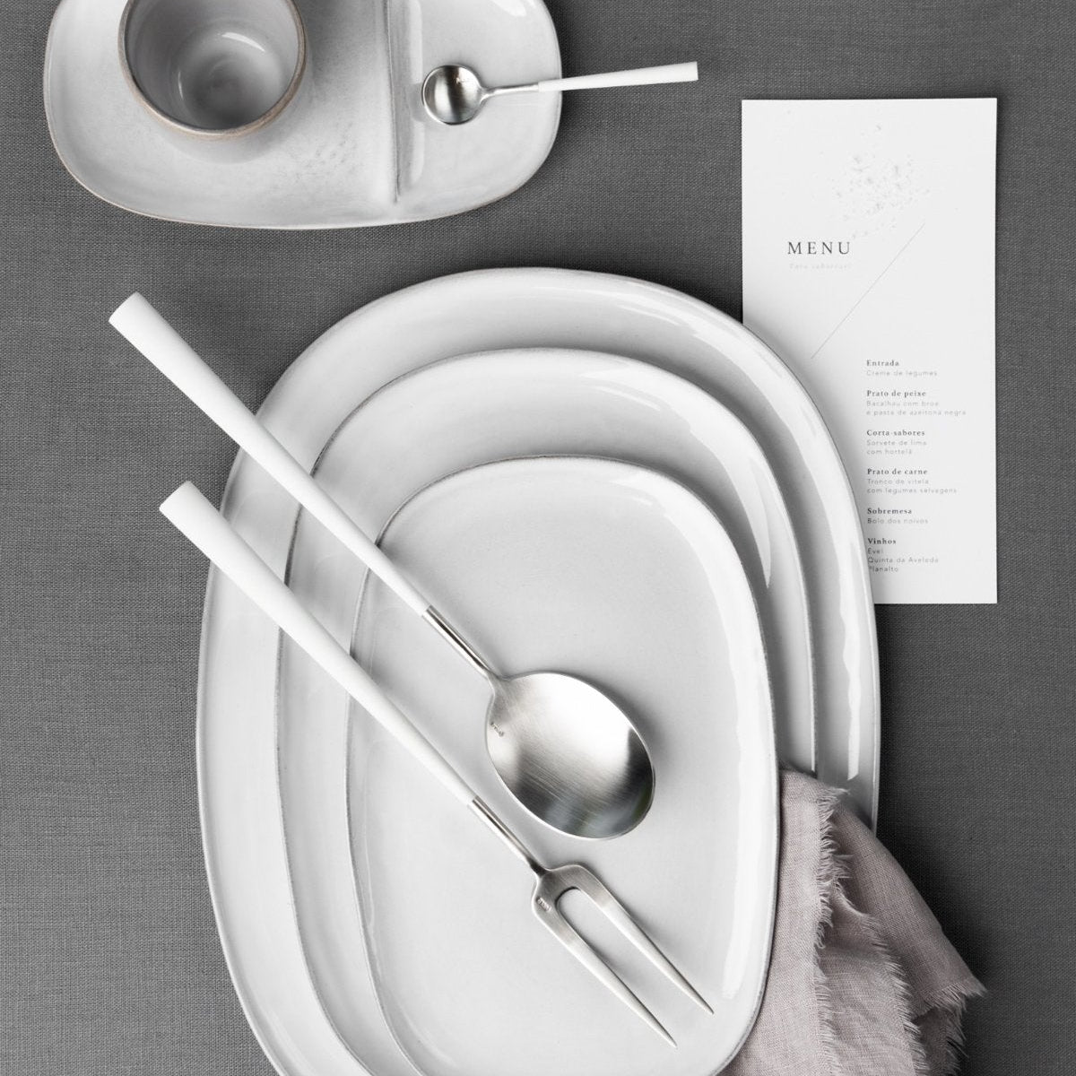 Belo Inox Neo White serving set with stainless steel serving fork and serving spoon on white ceramic plates.