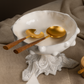 sophisticated lifestyle scene featuring Belo Inox Neo Wood salad servers with brushed gold metal heads and wooden handles resting inside a white ceramic bowl
