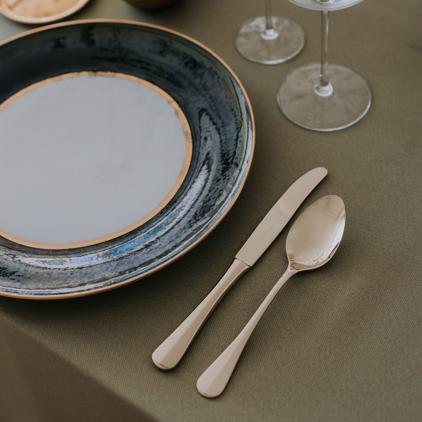 Palmela cutlery by Belo Inox arranged beside a ceramic plate and wine glasses in an elegant table setting