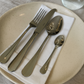Belo Inox Palmela polished stainless-steel cutlery set placed on a white napkin with neutral ceramic plates