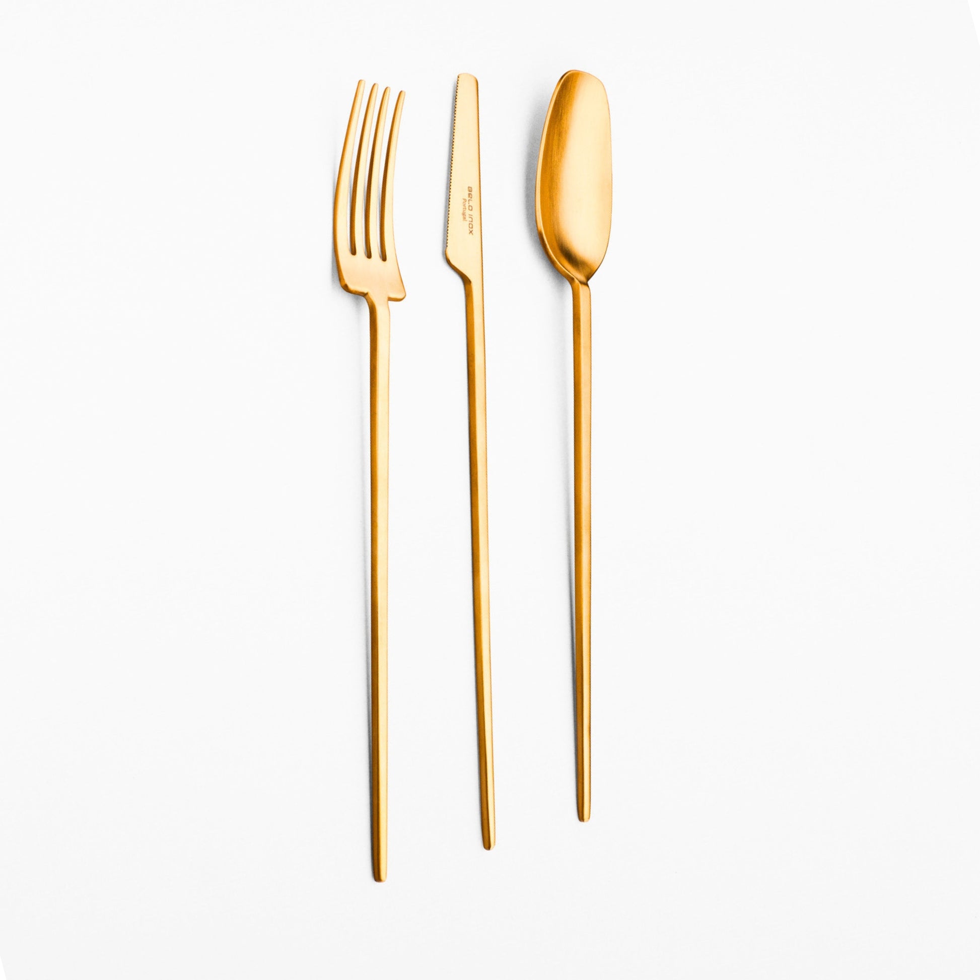 Belo Inox TWO gold polished cutlery set — modern long-handle spoon, knife and fork on a light background