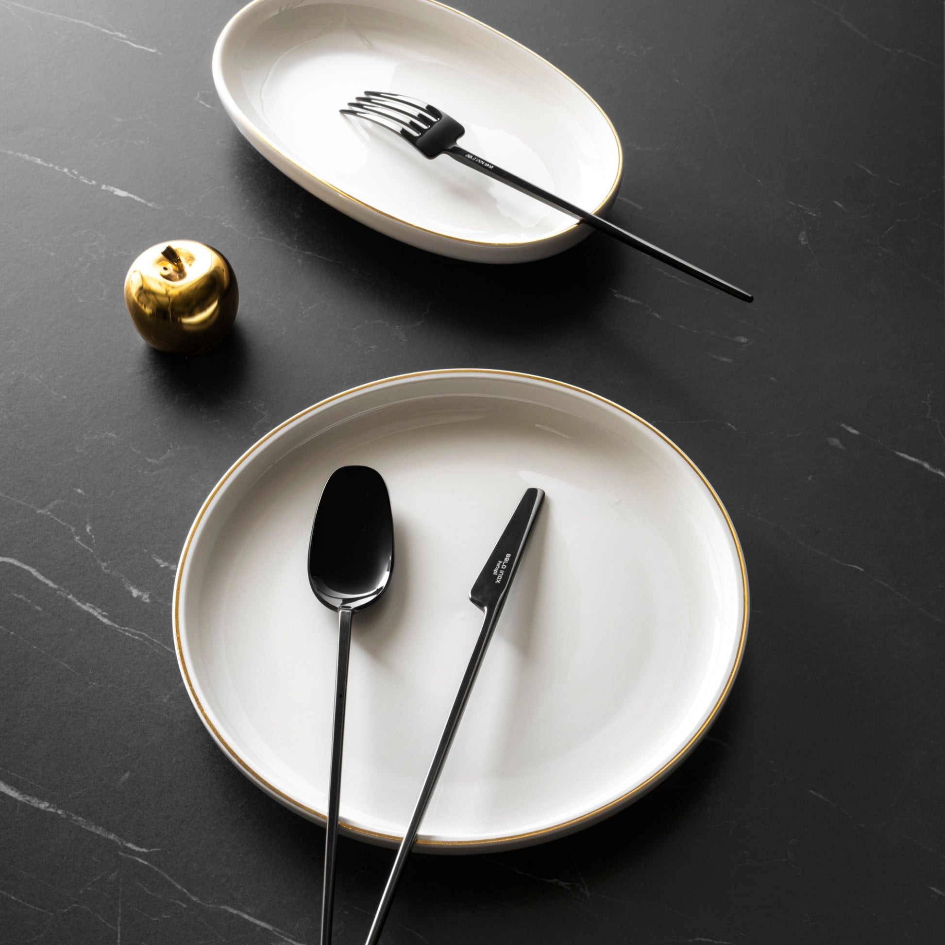Belo Inox TWO high-shine black PVD cutlery set displayed on elegant dark table setting with white plates