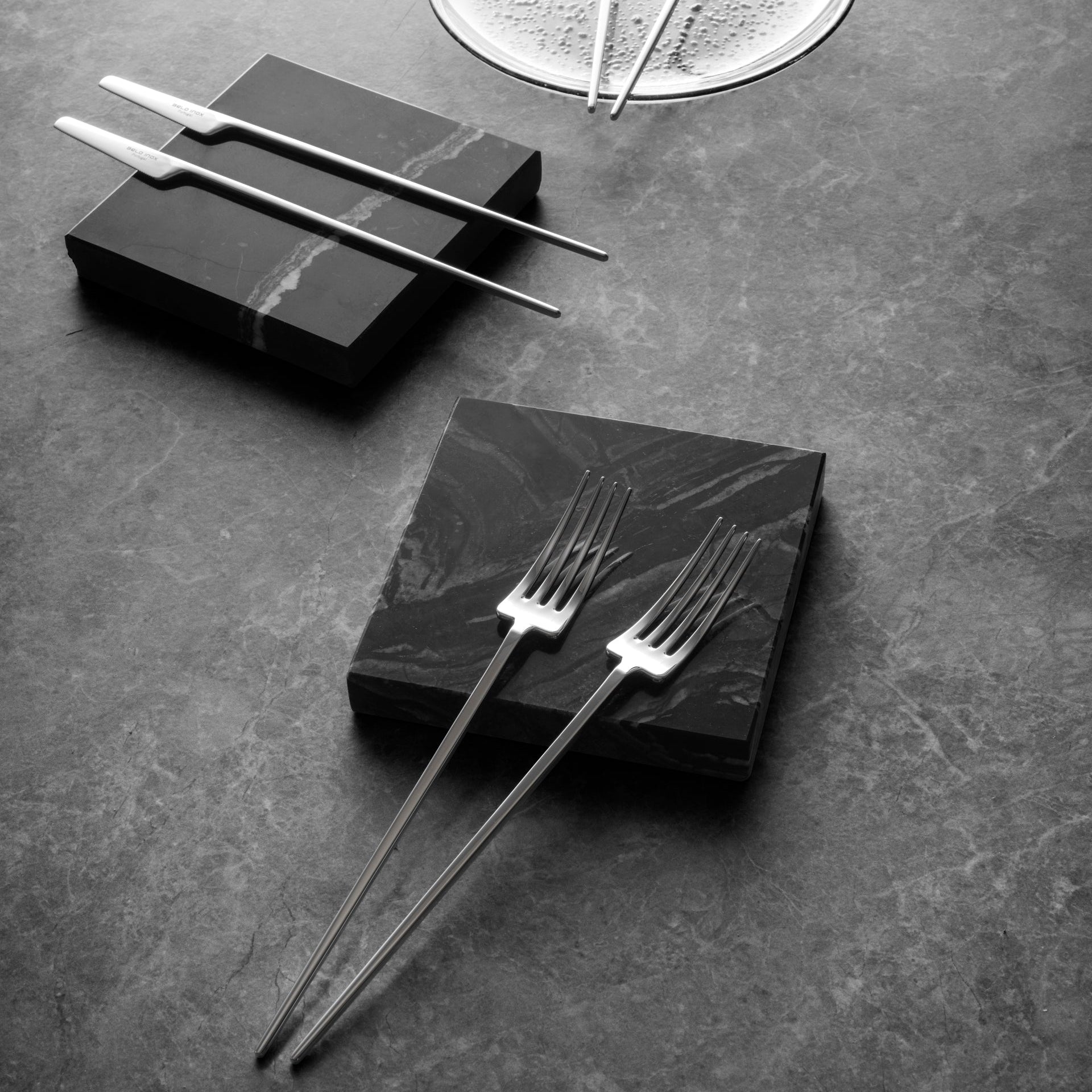 Belo Inox TWO Titanium Mirror cutlery set displayed on dark stone surface, featuring modern knife and forks in a luxurious ambience