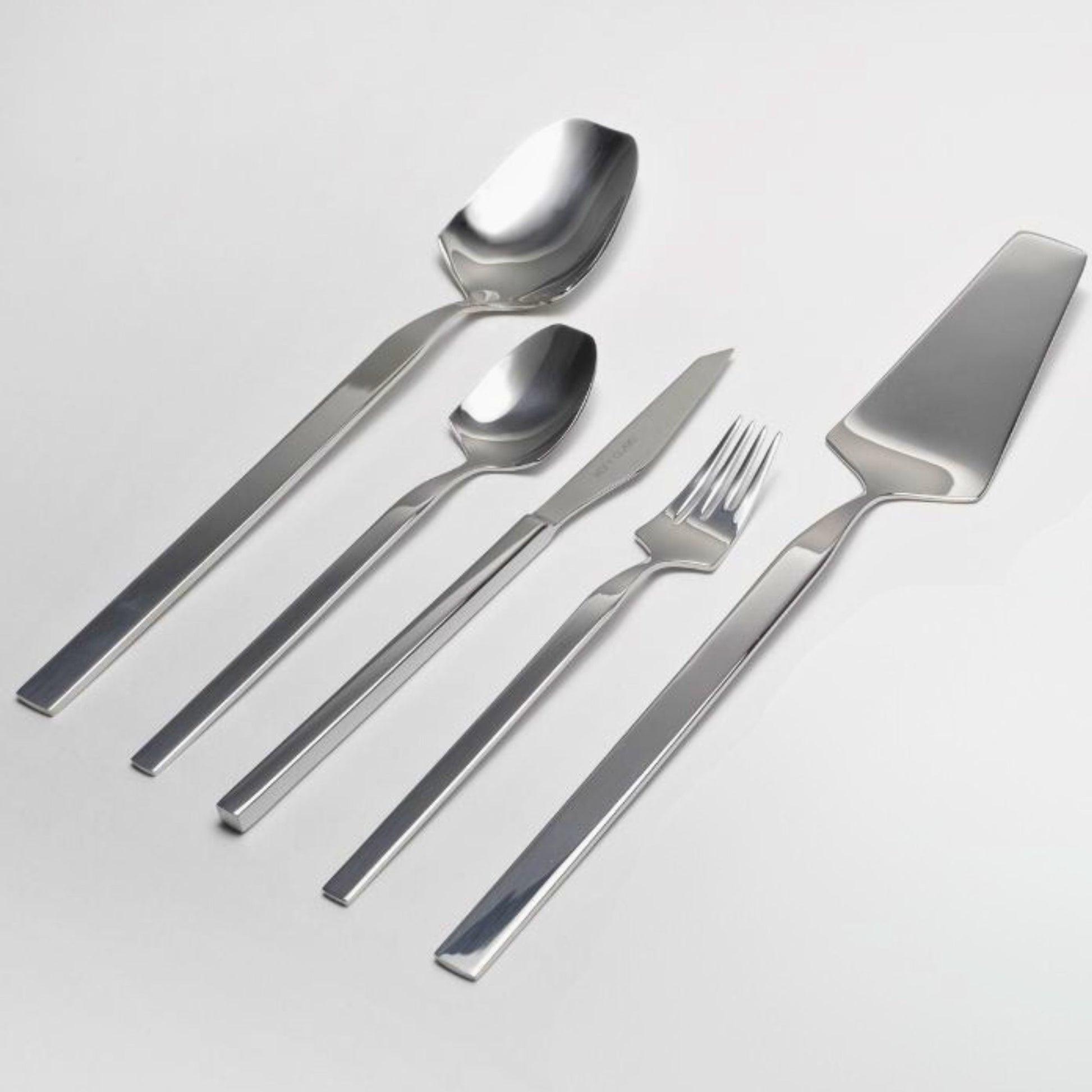 Belo Inox Vertice polished cutlery set featuring a cake server, dessert knife, dessert fork, dessert spoon, and serving spoon on a light background