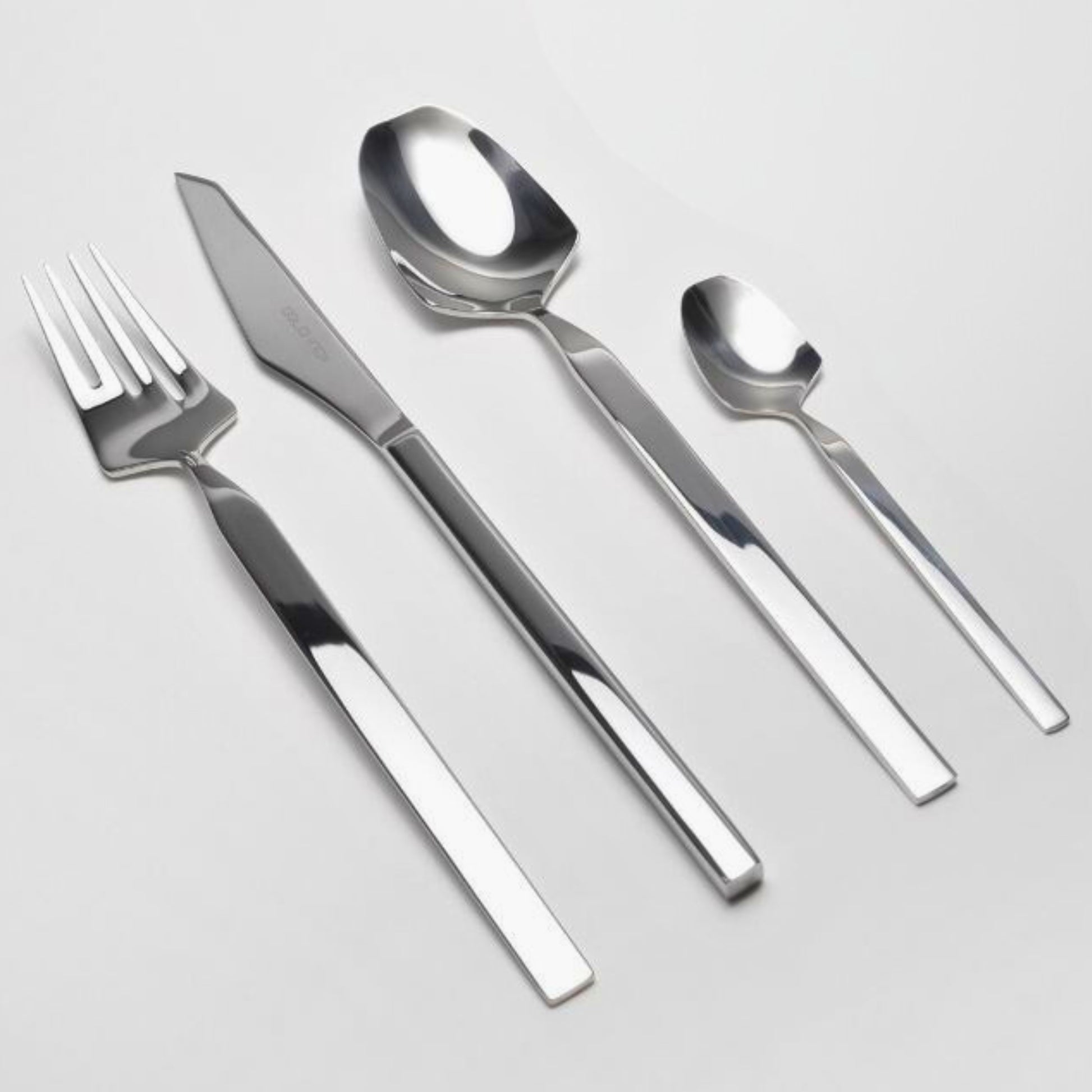 Belo Inox Vertice polished stainless steel flatware set featuring dinner knife, dinner fork, tablespoon and teaspoon on a light background