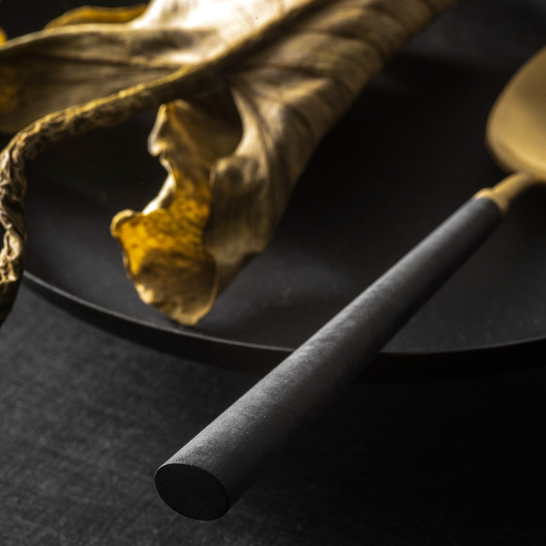 Close-up of Belo Inox Yume cutlery with black resin handle and brushed gold finish