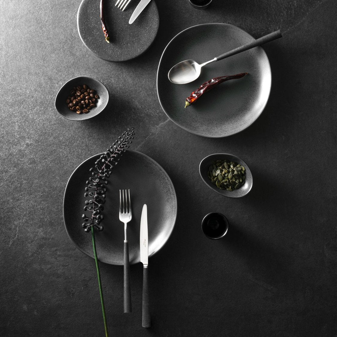 Modern table setting featuring Belo Inox Yume cutlery in brushed steel with black handles
