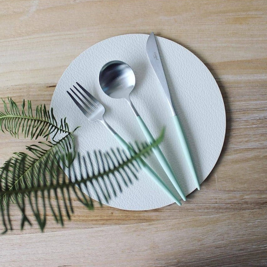 Cutipol GOA Celadon cutlery set arranged on a white textured plate with green fern leaves