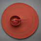 Red Cutipol Goa chopsticks resting on a matching red bowl and plate set against a gray background.
