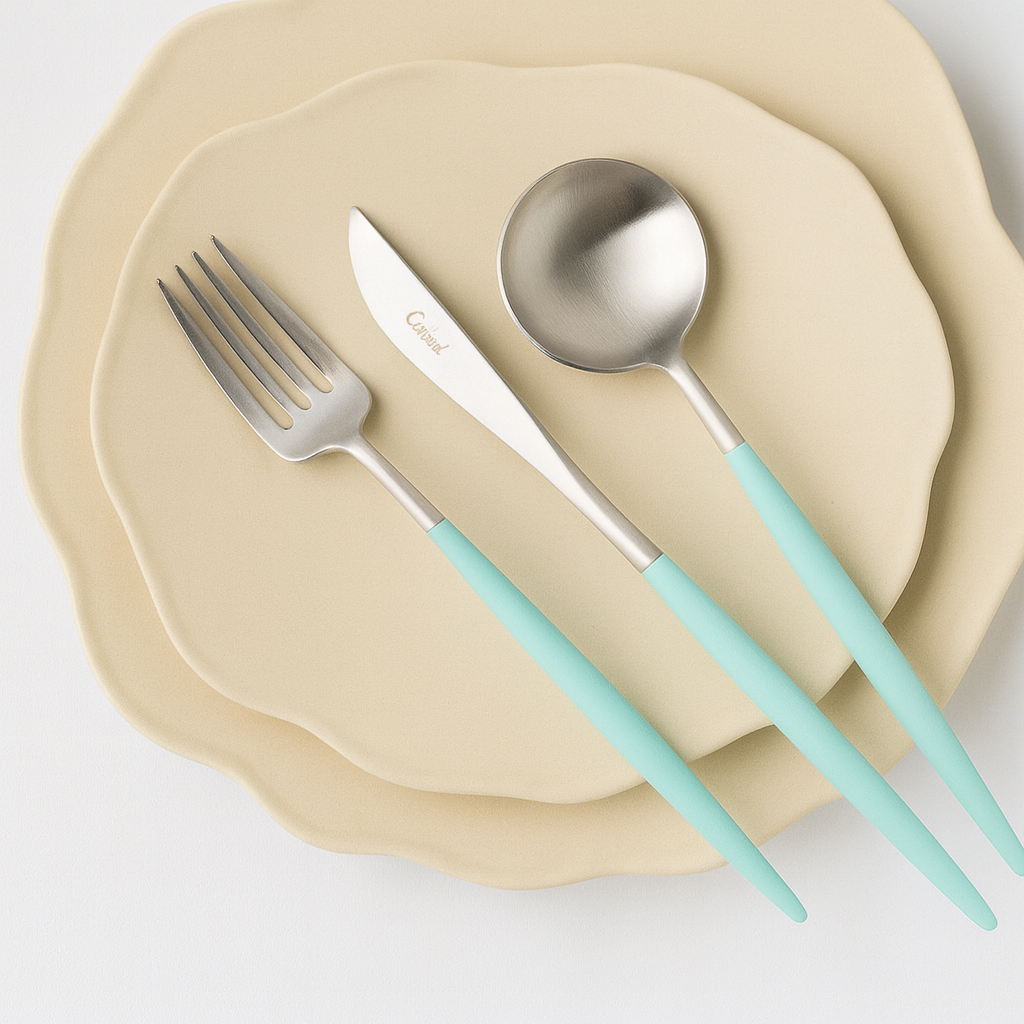 Cutipol Goa Turquoise cutlery set on a beige plate, premium Portuguese flatware with turquoise handles