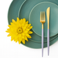 Cutipol GOA Violet Gold cutlery placed on layered blue ceramic plates with a decorative flower