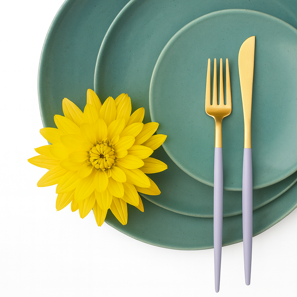 Cutipol GOA Violet Gold cutlery placed on layered blue ceramic plates with a decorative flower