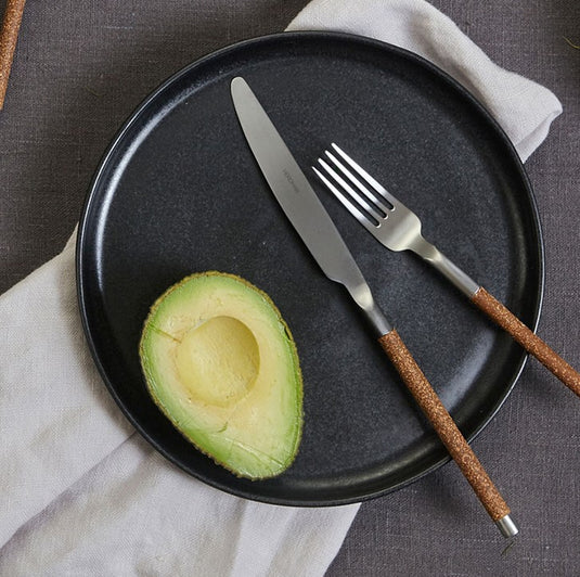 Herdmar NOHC cutlery set on a rustic table with ceramic plates, avocado, and natural linen – contemporary Portuguese design.