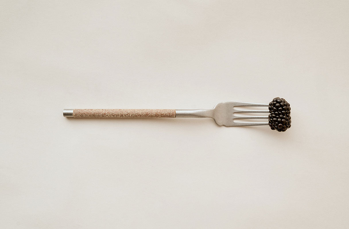 Herdmar NOHC fork with a blackberry on a light background – minimalist Portuguese tableware design.