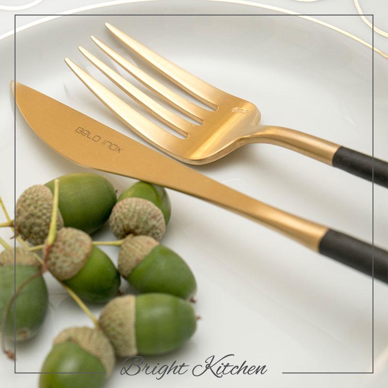 Close-up of Belo Inox Neo Black Gold cutlery knife and fork with matte black handles and 24K gold finish, made in Portugal, displayed on a white plate